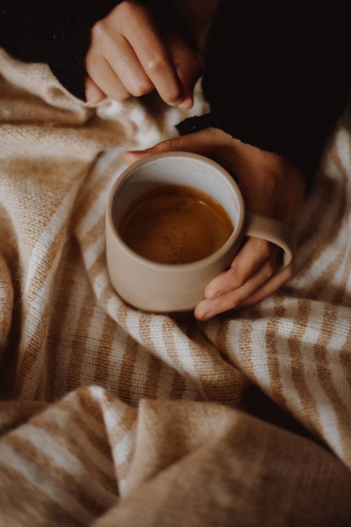 Person Holding A Hot Drink With A Blanket On